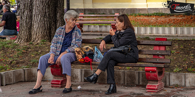 Старије жене седе на клупи и разговарају